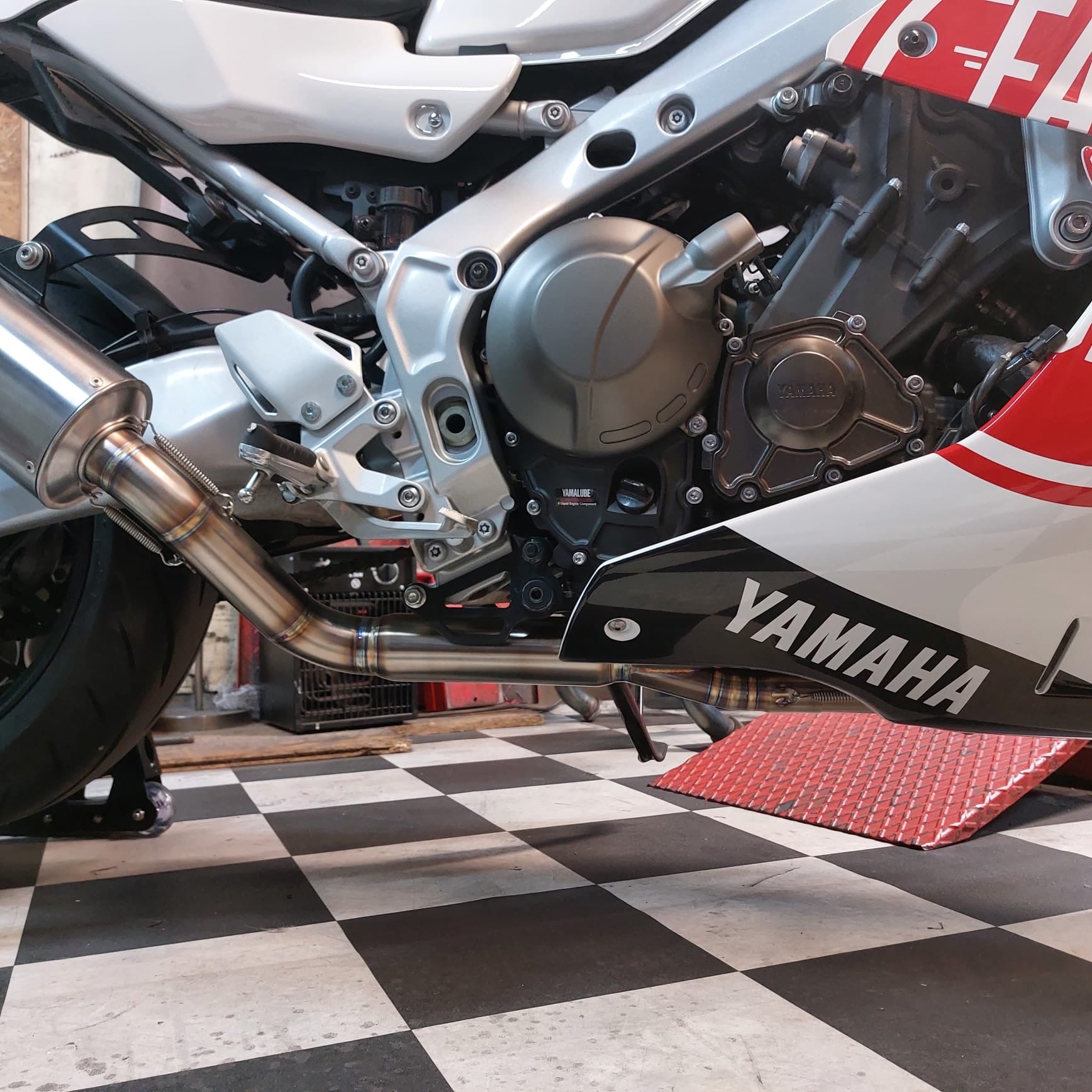 MAD Exhausts stainless steel header pipes on the Yamaha XSR900 GP, engine and mid-pipe visible above a chequered workshop floor