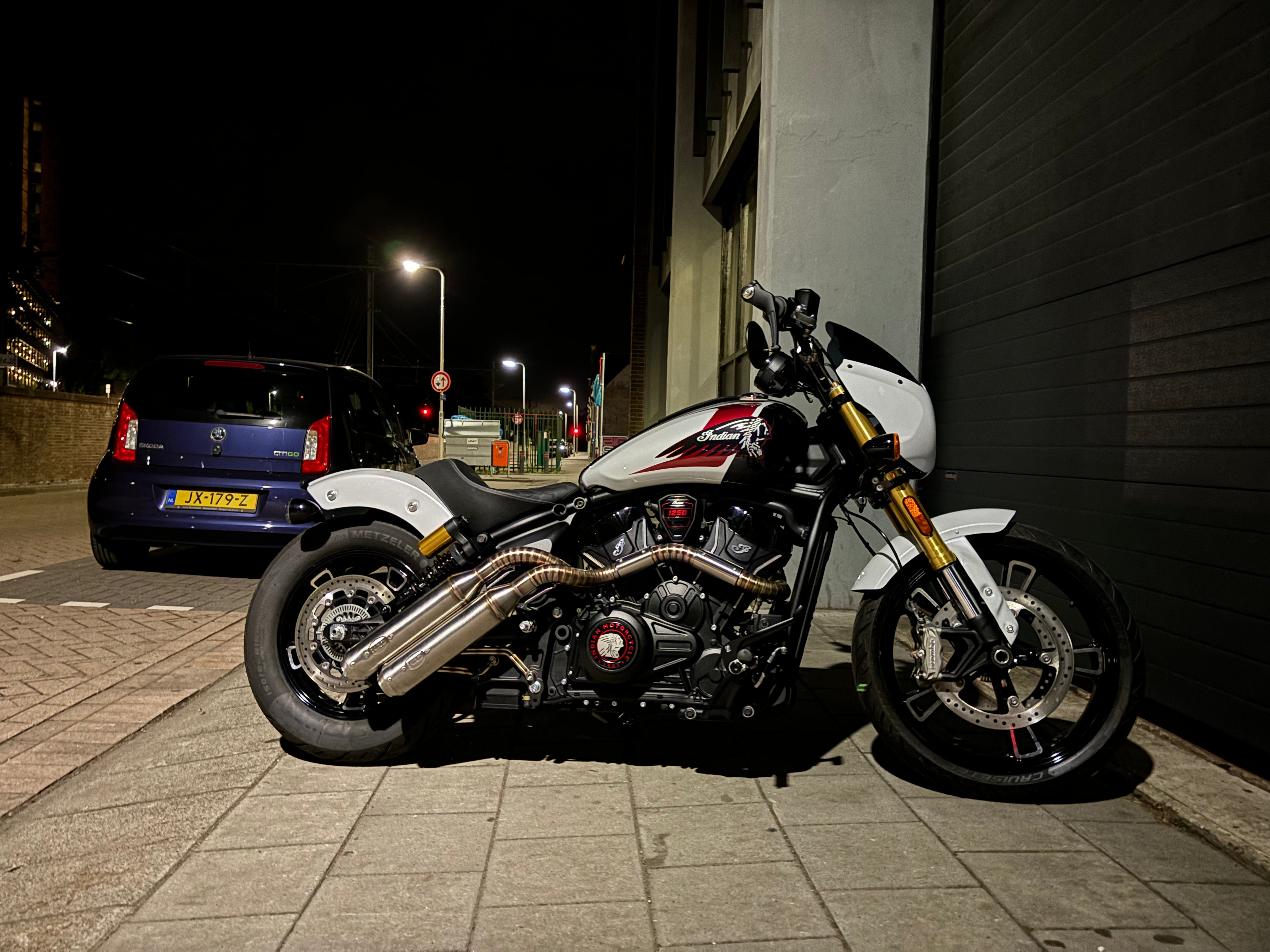 Indian Scout 1250 right-side view on a street at night, showing the MAD Exhausts down-swept twin silencers