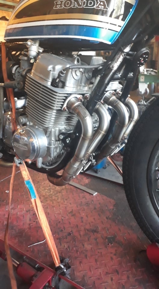 MAD Exhausts Cobra headers mounted on a blue and white Honda CB750, close-up of the engine on a workshop lift