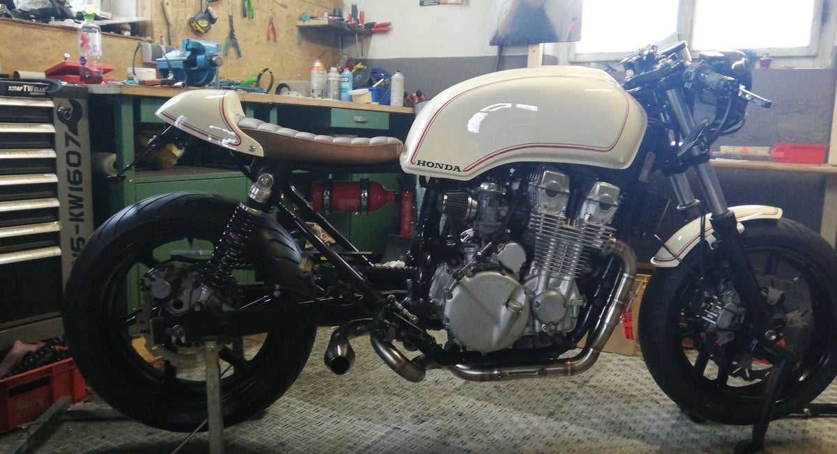 Honda CB750 cafe racer with cream and red tank fitted with the MAD Exhausts Cobra exhaust system, full side view in the workshop