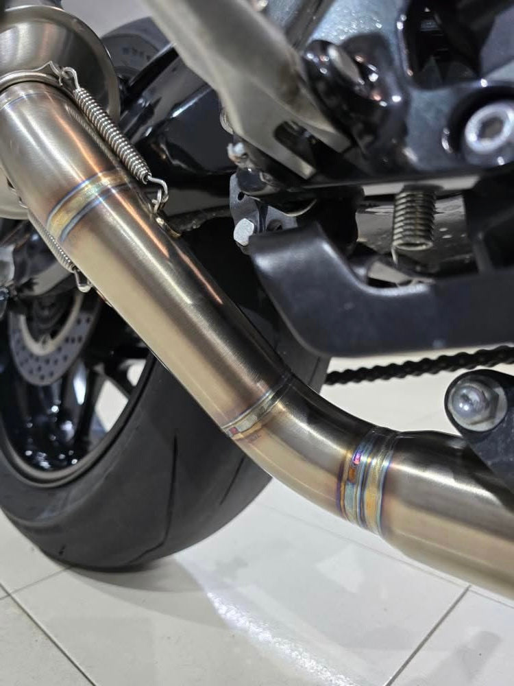 MAD Exhausts stainless steel link pipe for the Yamaha CP3 platform mounted near the rear wheel, spring-mounted connection visible