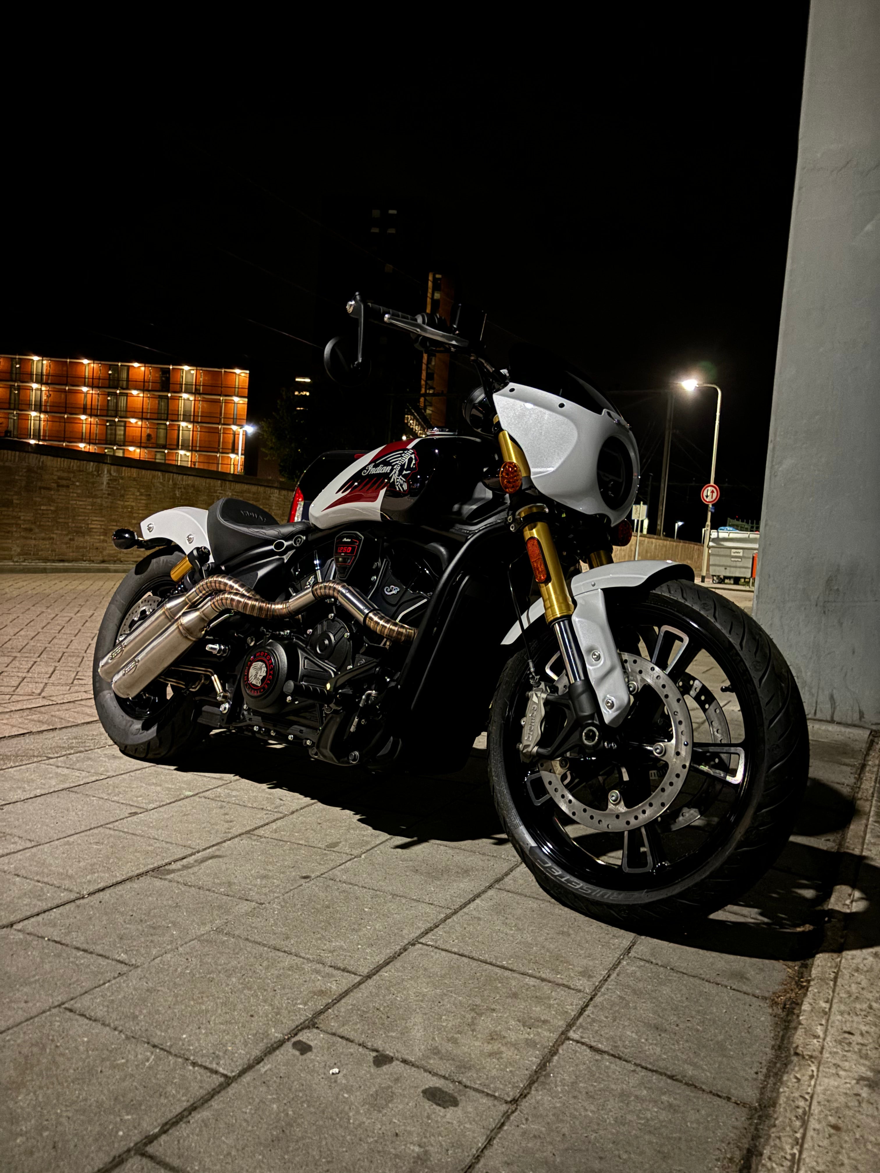 Indian Scout 1250 with the MAD Exhausts down-swept system, front three-quarter night shot on the street