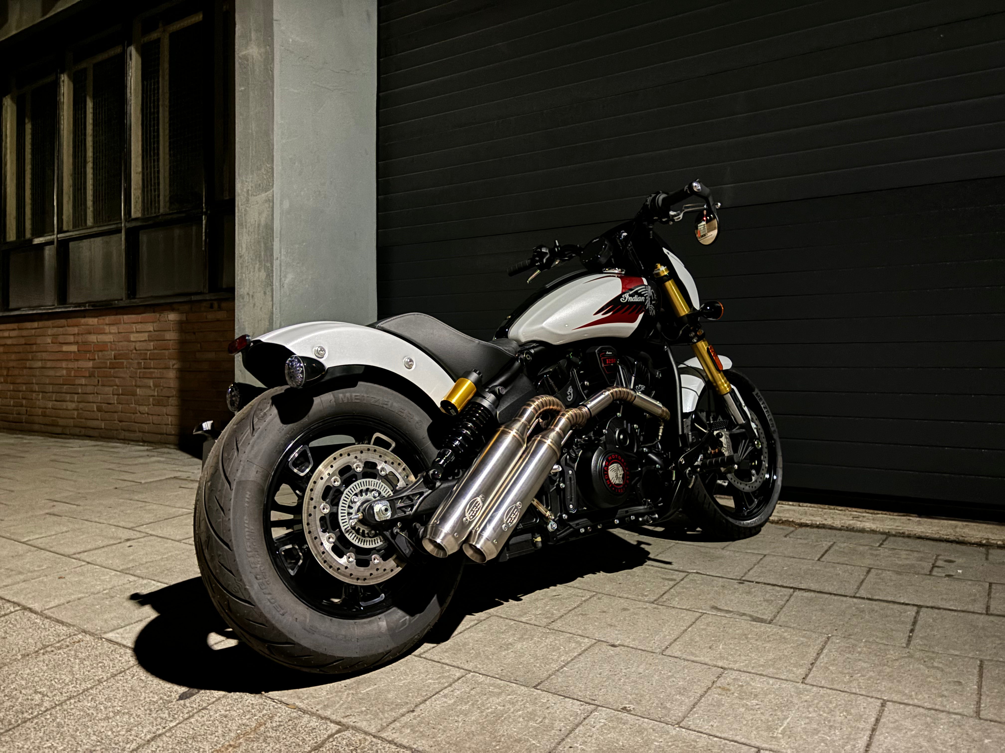Indian Scout 1250 full side view with the MAD Exhausts down-swept twin silencers, parked by a garage door