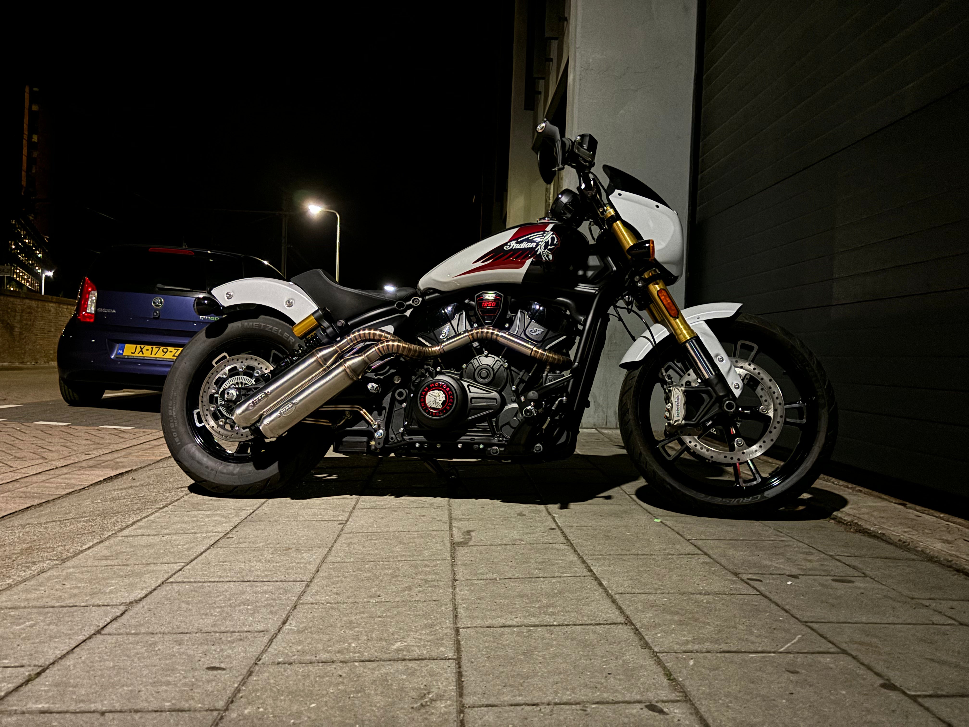 Low-angle side view of the Indian Scout 1250 at night with the MAD Exhausts down-swept twin silencers