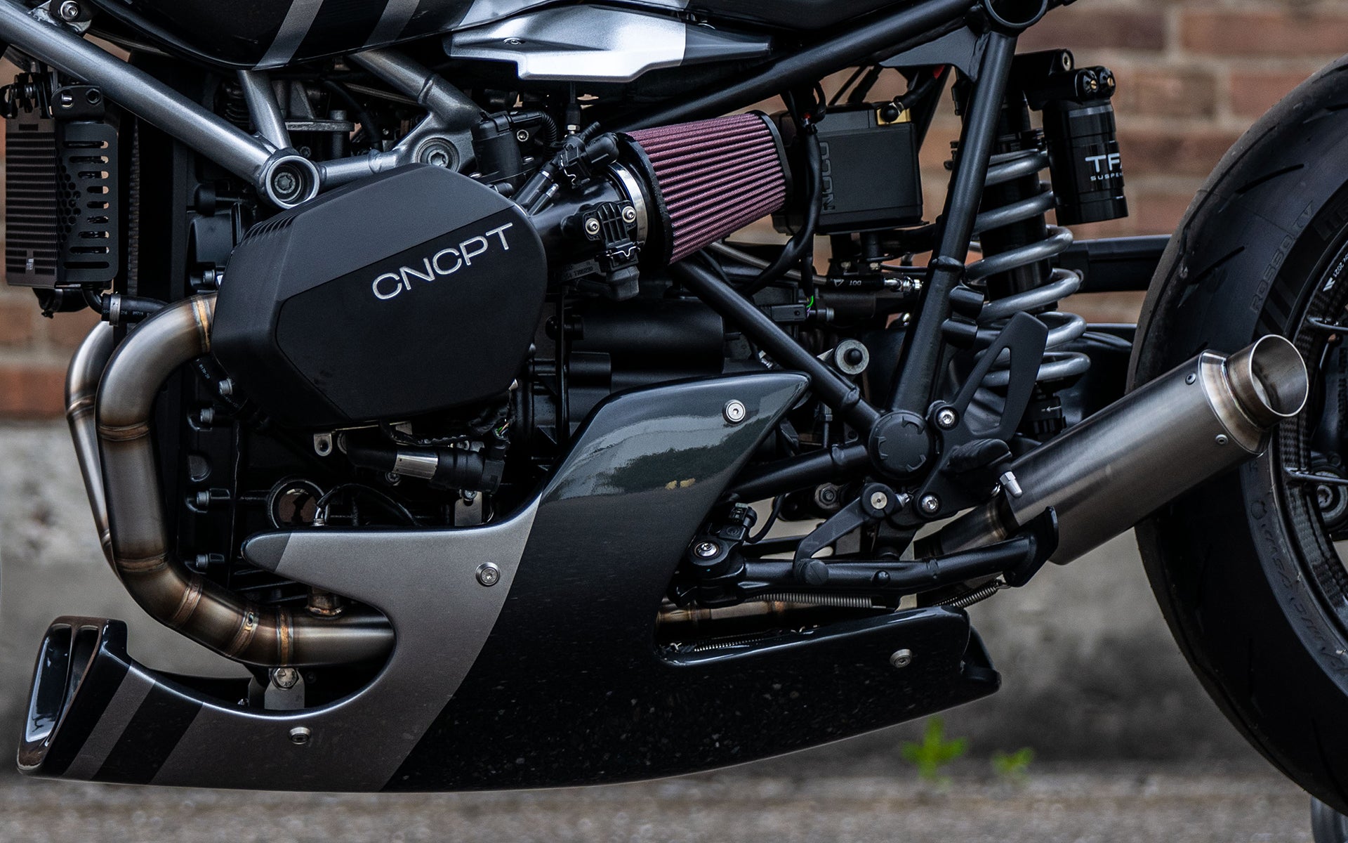 MAD Exhausts BMW R nineT 2-in-1 exhaust system mounted on a black café racer, close-up of engine and header pipes