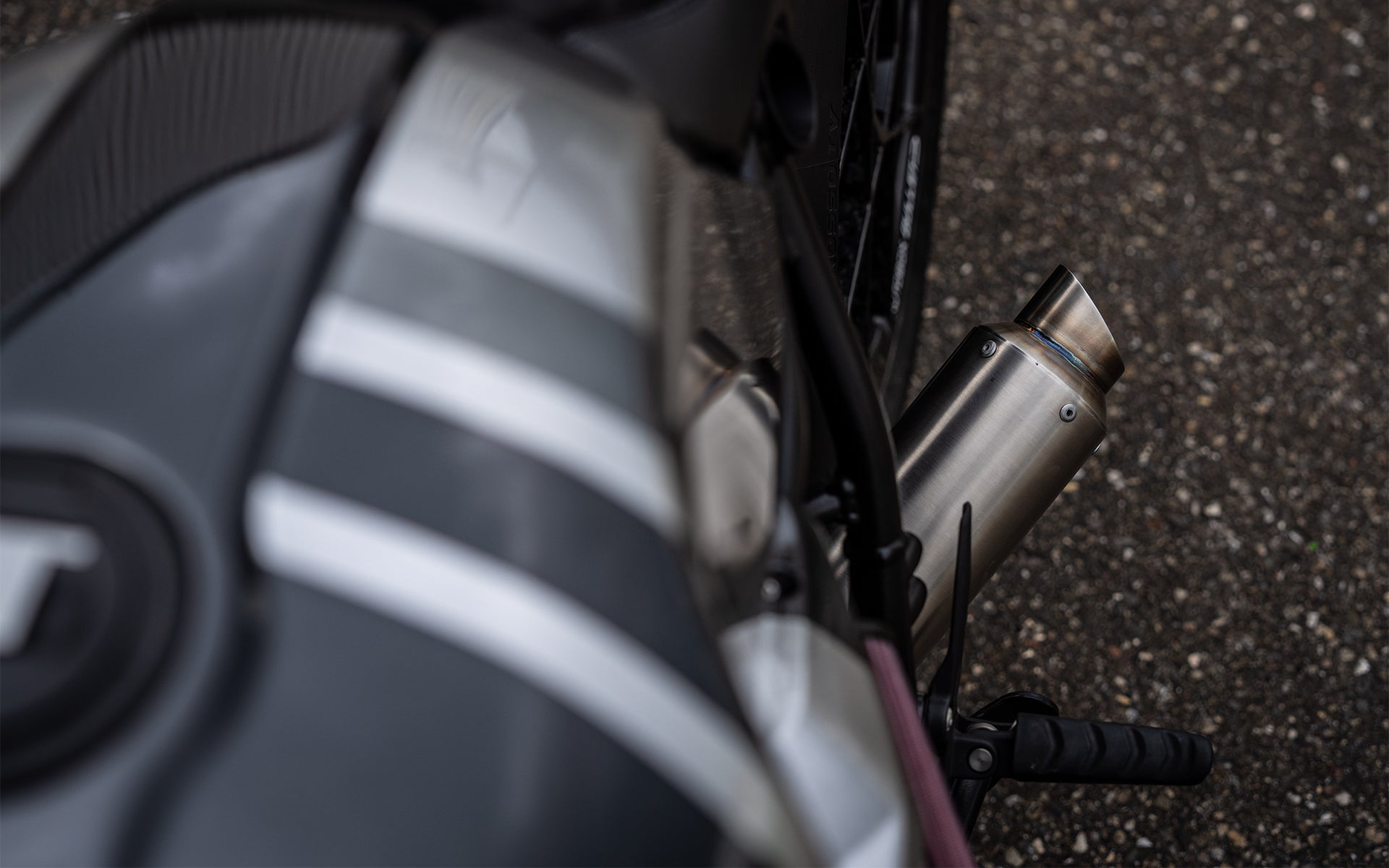 Rear detail of the MAD Exhausts muffler outlet on the Powerbrick BMW R nineT café racer, mounted below the seat