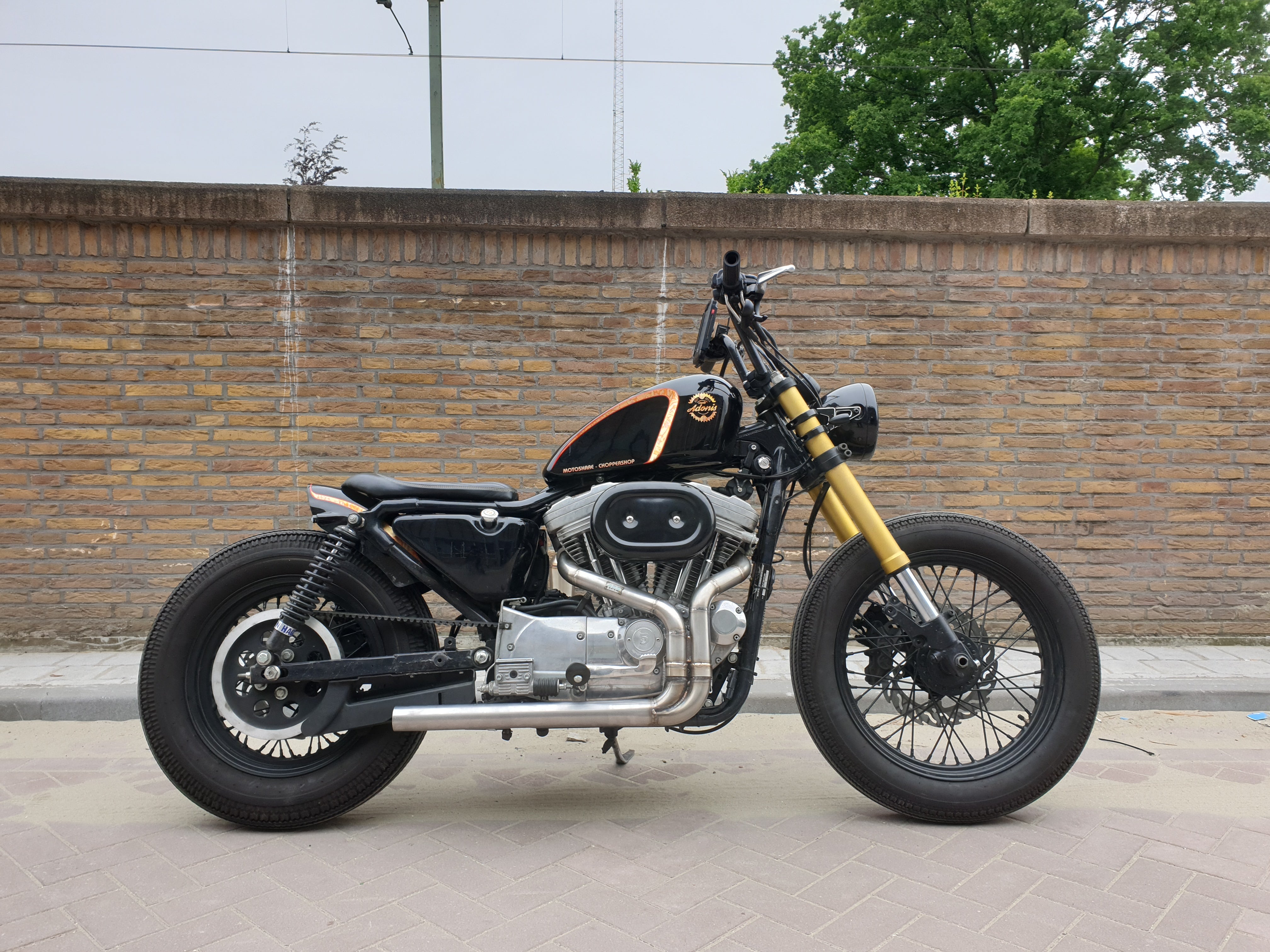 Black Harley-Davidson Sportster bobber with the MAD Exhausts system fitted, full side view on the street