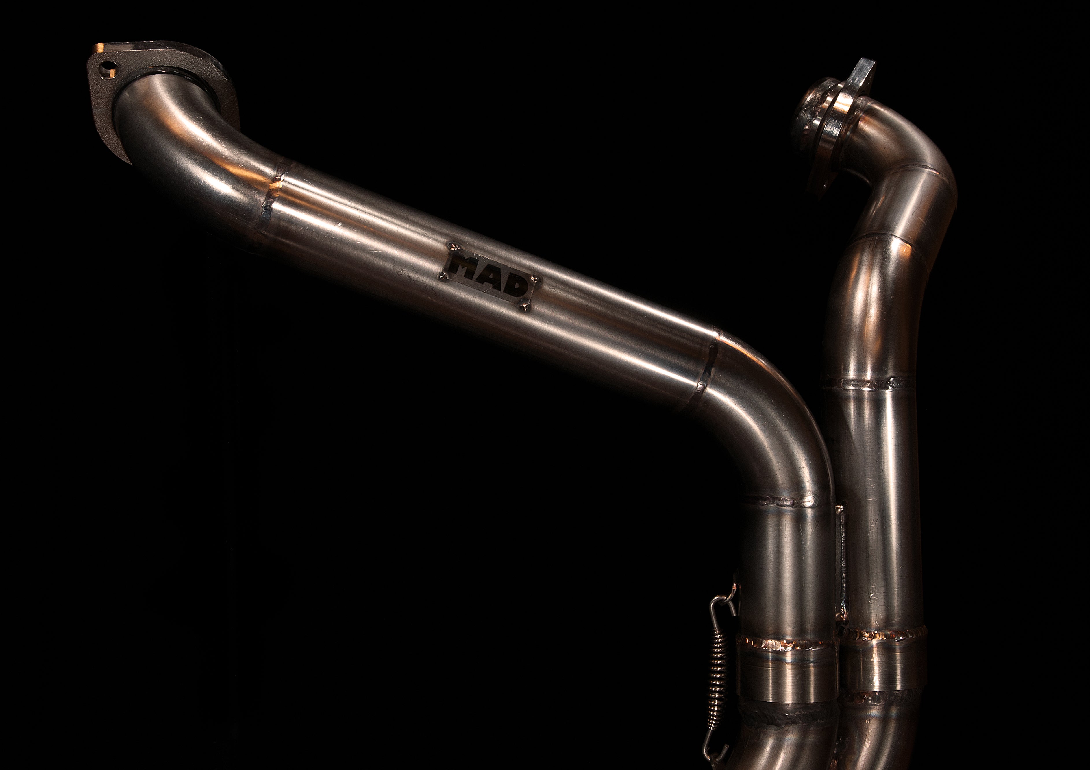 MAD Exhausts Harley-Davidson Sportster header showing both mounting flanges and MAD logo, studio photo on black