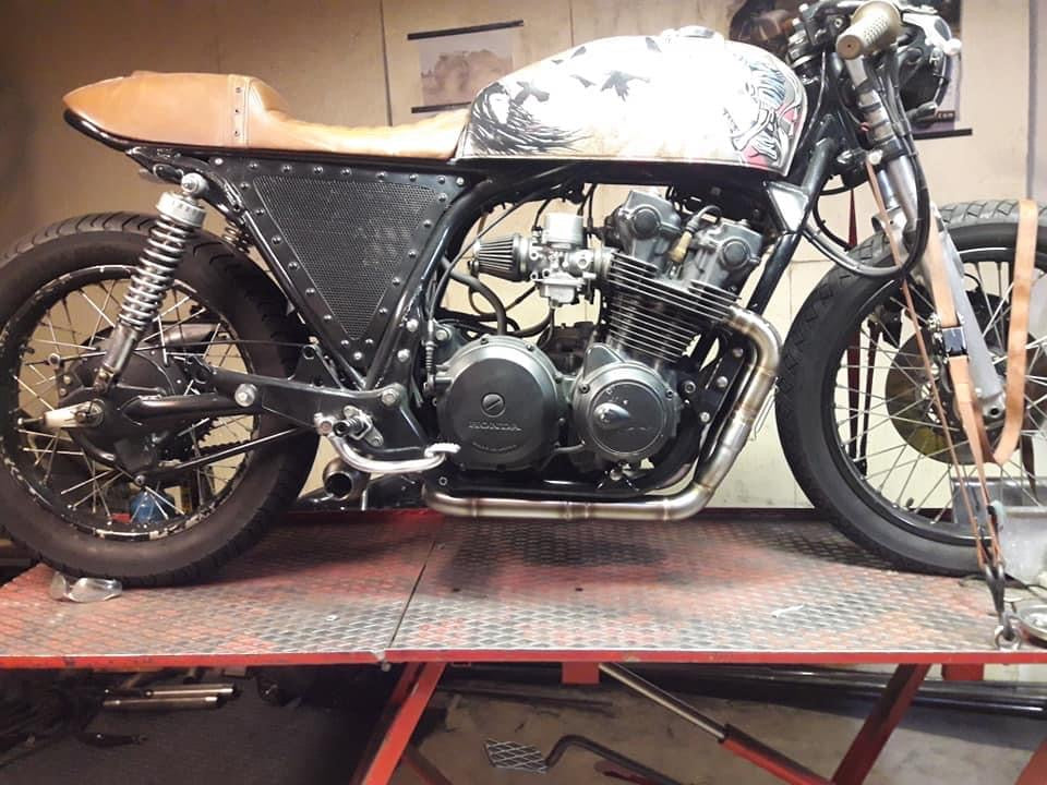 Honda CB750 cafe racer with airbrushed eagle tank and MAD Exhausts Cobra system, full side view on the workshop lift