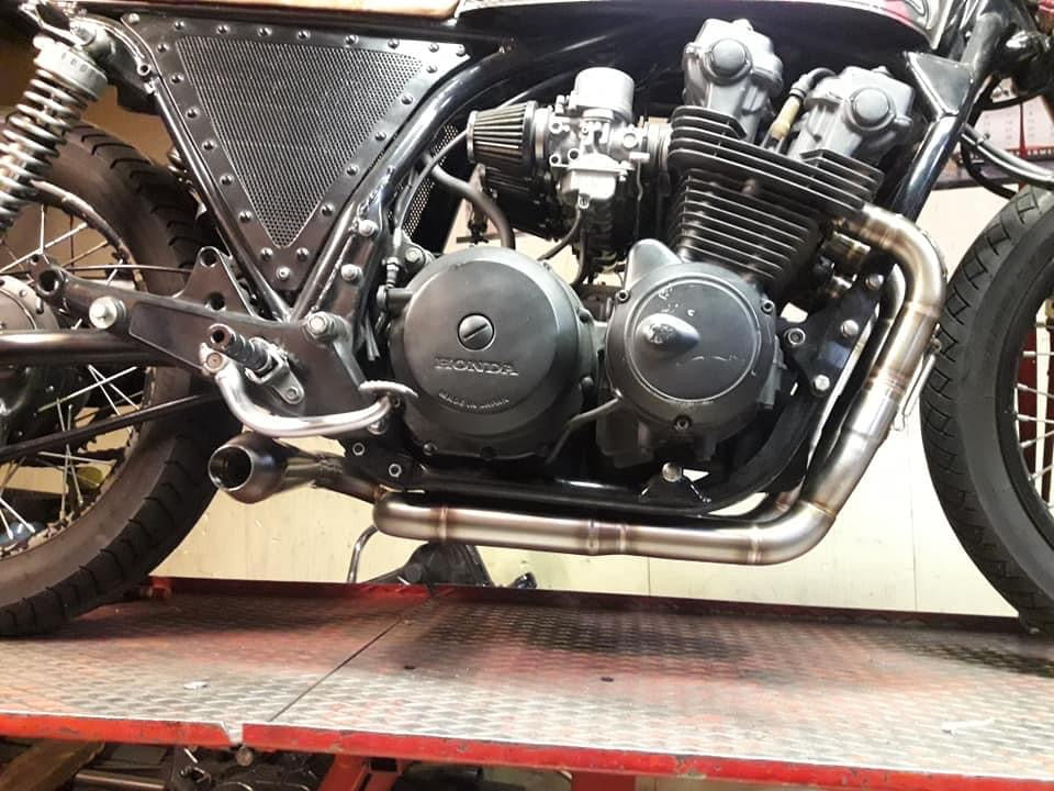 MAD Exhausts Cobra headers routed under the Honda CB750 four-cylinder engine, side view on the workshop lift