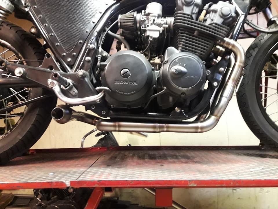 Side view of the MAD Exhausts Cobra system fully mounted on the Honda CB750 engine, showing header routing and silencer outlet