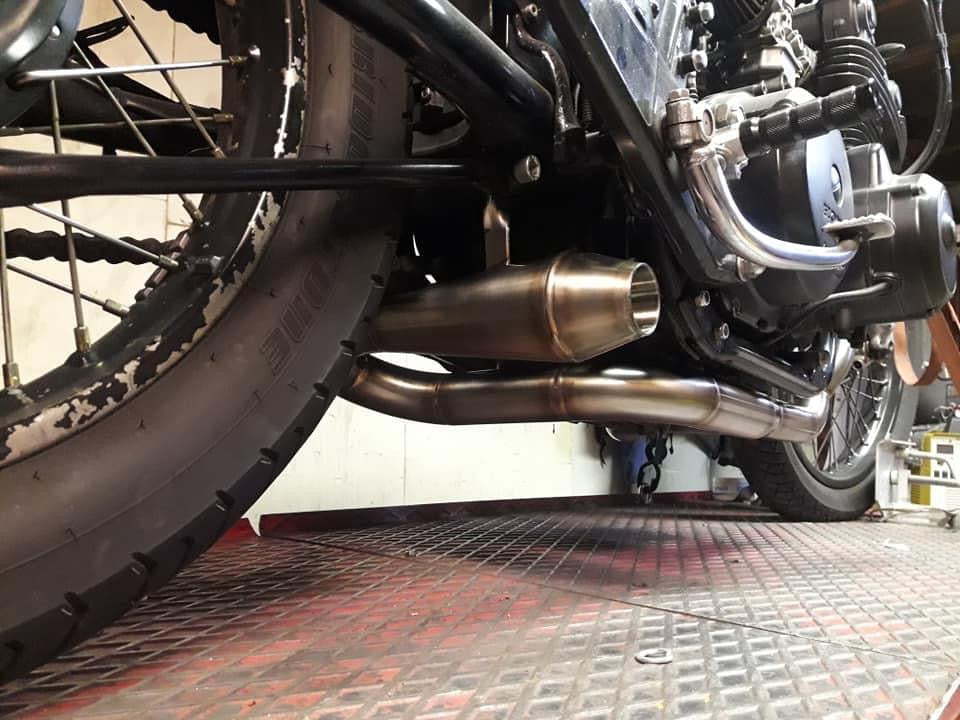 Cone silencer outlet of the MAD Exhausts Cobra system mounted under the Honda CB750 near the rear wheel, low-angle view